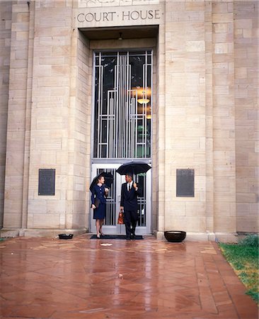 simsearch:846-05648291,k - 1990s COUPLE OUTSIDE OF COURTHOUSE IN THE RAIN WITH UMBRELLAS Stock Photo - Rights-Managed, Code: 846-09085325