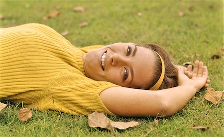 1960s SMILING YOUNG BRUNETTE WOMAN LYING IN GRASS AUTUMN LEAVES LOOKING AT CAMERA WEARING YELLOW POOR BOY SWEATER AND HEADBAND Stock Photo - Rights-Managed, Code: 846-09085327