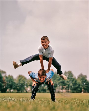 simsearch:846-05646032,k - 1960s BOYS PLAYING LEAP FROG ONE JUMPING OVER THE OTHER'S BACK LOOKING AT CAMERA Stock Photo - Rights-Managed, Code: 846-09085337