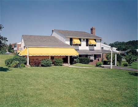 1960s 1970s SUBURBAN HOME RESIDENTIAL NEIGHBORHOOD WHITE WITH BLACK SHUTTERS YELLOW AWNINGS FRONT LAWN Stock Photo - Rights-Managed, Code: 846-09161457