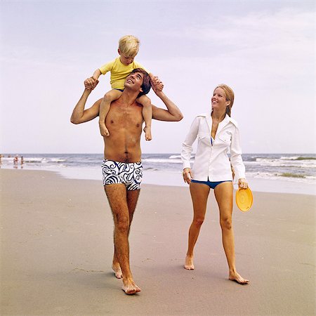 simsearch:846-09012864,k - 1970s YOUNG FAMILY WALKING DOWN BEACH TODDLER RIDING ON FATHERS SHOULDERS Stock Photo - Rights-Managed, Code: 846-09161452