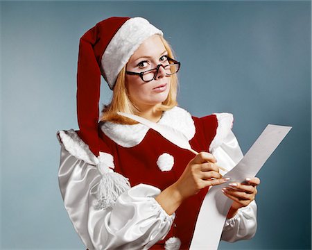 santa claus funny - 1960s WOMAN IN CHRISTMAS SANTA'S HELPER COSTUME AND CAP WEARING GLASSES LOOKING AT CAMERA CHECKING NAUGHTY OR NICE LIST Stock Photo - Rights-Managed, Code: 846-09161475