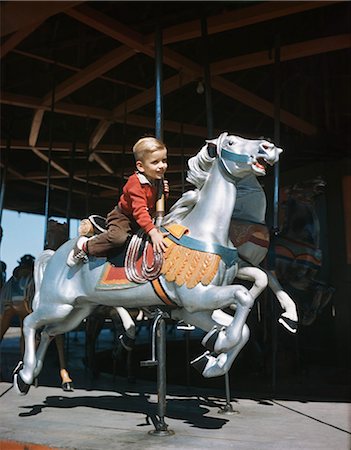 simsearch:846-05645665,k - 1950s HAPPY SMILING LITTLE BOY RIDING GALLOPING CAROUSEL HORSE ON MERRY GO ROUND Stock Photo - Rights-Managed, Code: 846-09161490