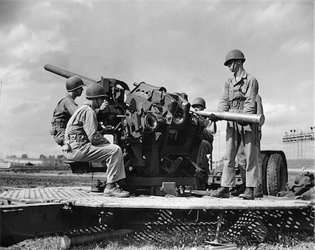 simsearch:846-05647657,k - 1940s CREW OF FOUR WORLD WAR II SOLDIERS MANNING ARTILLERY CANNON LOADING SHELL INTO BREECH OF GUN Photographie de stock - Rights-Managed, Code: 846-09161588