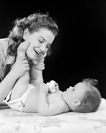 1940s MOTHER PLAYING WITH BABY GIRL HOLDING BABY'S LEGS UP TO TOUCH MOM'S FACE Foto de stock - Con derechos protegidos, Código: 846-09181573