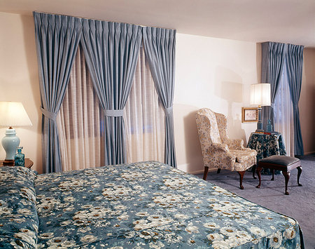 simsearch:846-03164705,k - 1960s 1970s BEDROOM INTERIOR KING SIZE BED BLUE CURTAINS FLORAL BEDSPREAD AND CARPET COMFORTABLE CHAIRS Stockbilder - Lizenzpflichtiges, Bildnummer: 846-09181803
