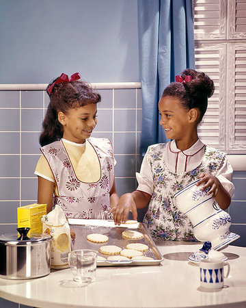 simsearch:846-02794589,k - 1960s TWO SMILING AFRICAN AMERICAN GIRLS SISTERS IN KITCHEN BAKING COOKIES Stock Photo - Rights-Managed, Code: 846-09181813
