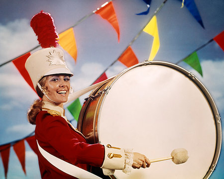 drum (instrument) - 1960s 1970s WOMAN DRUM MAJORETTE LOOKING AT CAMERA RED UNIFORM WHITE HELMUT SMILING BEATING LARGE BASE DRUM Stock Photo - Rights-Managed, Code: 846-09181837