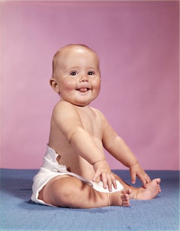1960s SMILING BABY WEARING CLOTH DIAPER SITTING ON BLUE BLANKET STICKING OUT TONGUE Stock Photo - Rights-Managed, Code: 846-02794044