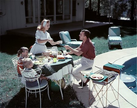 1950s FAMILY IN BACKYARD HAVING PICNIC FROM GRILL NEAR SWIMMING POOL Stock Photo - Rights-Managed, Code: 846-02794086