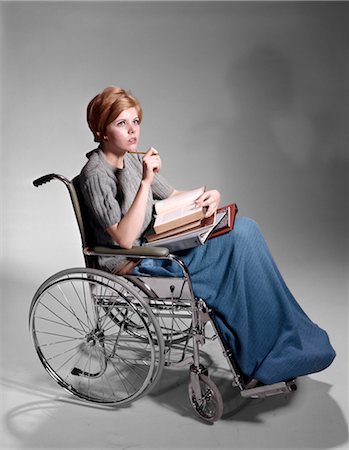 1960s SERIOUS YOUNG WOMAN STUDENT SITTING IN WHEELCHAIR PILE OF BOOKS ON LAP Stock Photo - Rights-Managed, Code: 846-02794714