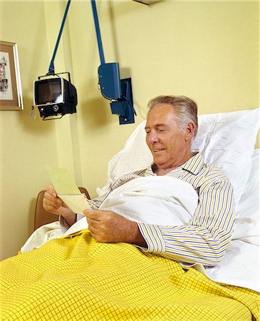 1980s SMILING SENIOR MAN IN HOSPITAL BED OPENING MAIL LOOKING AT INSURANCE CHECK Foto de stock - Con derechos protegidos, Código: 846-02794772