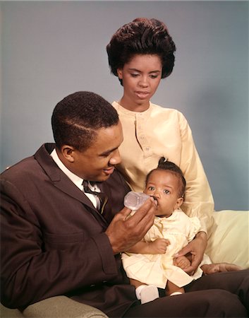 1960s AFRICAN AMERICAN FAMILY MOTHER WATCHING FATHER FEEDING BABY WITH BOTTLES Stock Photo - Rights-Managed, Code: 846-02794885