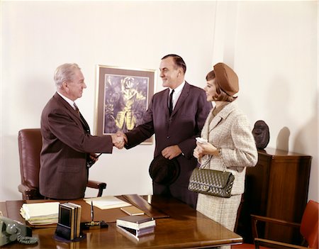 COUPLE STANDING AT DESK WITH EXECUTIVE MEN SHAKING HANDS INDOOR MAN WOMAN THREE BANK LOAN Stock Photo - Rights-Managed, Code: 846-02794915