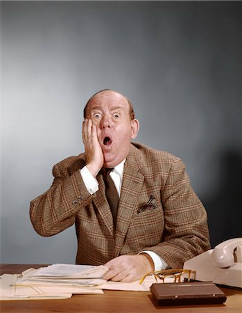 simsearch:846-02792220,k - 1960s SHOCKED BALDING EXECUTIVE WITH HAND TO CHEEK SITTING AT DESK Stock Photo - Rights-Managed, Code: 846-02794983