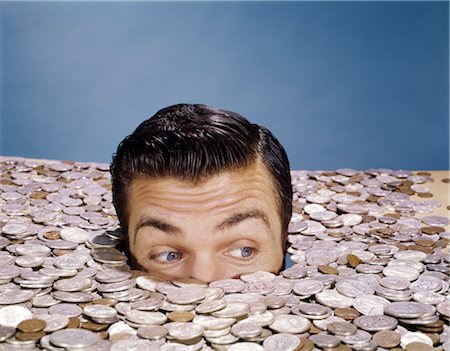 1960s TOP OF HEAD AND EYES OF MAN LOOKING OUT FROM PILE OF COINS STUDIO SYMBOLIC CURRENCY Foto de stock - Con derechos protegidos, Código: 846-02795025