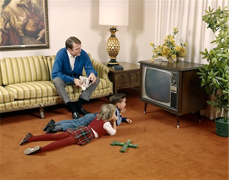 1960s FAMILY MAN FATHER SITTING ON LIVING ROOM COUCH WITH BOY SON AND GIRL DAUGHTER LYING ON FLOOR WATCHING TELEVISION TOGETHER Stock Photo - Rights-Managed, Code: 846-02795222