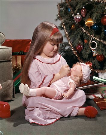 picture baby christmas - 1970s YOUNG GIRL NIGHTGOWN AND SLIPPERS SITTING BY CHRISTMAS TREE GIVING DOLL BABY A BOTTLE Stock Photo - Rights-Managed, Code: 846-02795302