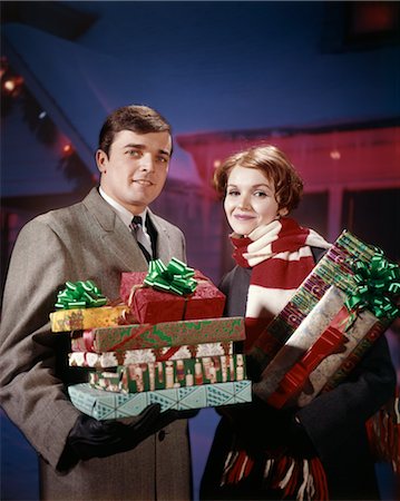 retro woman with christmas presents - 1960s 1970s COUPLE MAN WOMAN HOLDING STOCK PRESENTS GIFTS IN FRONT OF HOUSE DECORATED WITH LIGHTS STUDIO Stock Photo - Rights-Managed, Code: 846-02795303