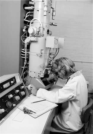 simsearch:846-02796653,k - 1970s SIDE VIEW OF WOMAN IN LAB COAT LOOKING THROUGH ELECTRON MICROSCOPE Stock Photo - Rights-Managed, Code: 846-02795378