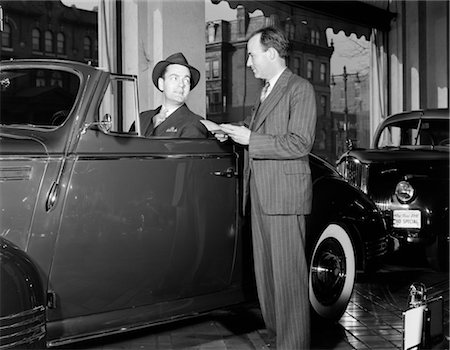 1940s SMILING MAN HAT SITTING CONVERTIBLE COUPE TOP DOWN TALKING SALESMAN PIN STRIPE SUIT AUTOMOBILE SHOWROOM Stock Photo - Rights-Managed, Code: 846-02795403