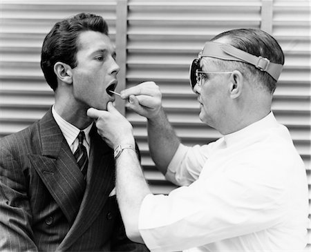 doctors with person in a suit - 1930s 1940s DOCTOR EXAMINING THROAT OF YOUNG MAN PATIENT Stock Photo - Rights-Managed, Code: 846-02795478