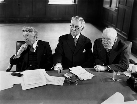 1930s 1940s GROUP OF THREE ELDERLY BUSINESSMEN SITTING AT CONFERENCE TABLE WITH ATTENTION DIRECTED TO SPEAKER NOT SHOWN Stock Photo - Rights-Managed, Code: 846-02795825