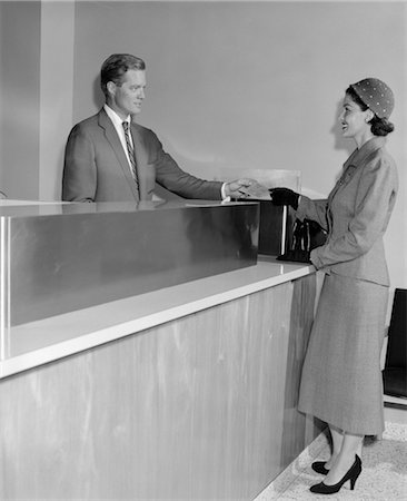 1950s BANK TELLER WOMAN MAN PARTITION FINANCE MONEY SUIT HAT Stock Photo - Rights-Managed, Code: 846-02796091