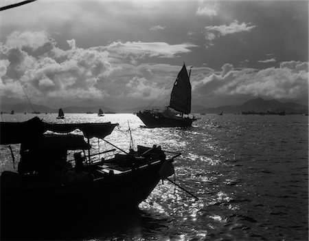 1920s 1930s DRAMATIC SUNSET HARBOR WITH SILHOUETTED CHINESE JUNKS AND BOATS HONG KONG CHINA Stock Photo - Rights-Managed, Code: 846-02796281