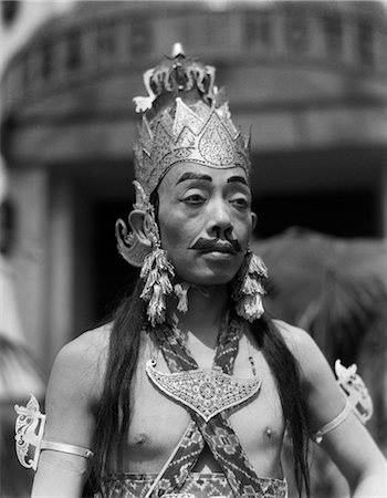 1920s 1930s MAN MALE JAVANESE DANCER IN COSTUME PORTRAIT CROWN EARRINGS MAKEUP FAKE MOUSTACHE EYEBROWS JAVA INDONESIA Stock Photo - Rights-Managed, Code: 846-02796391
