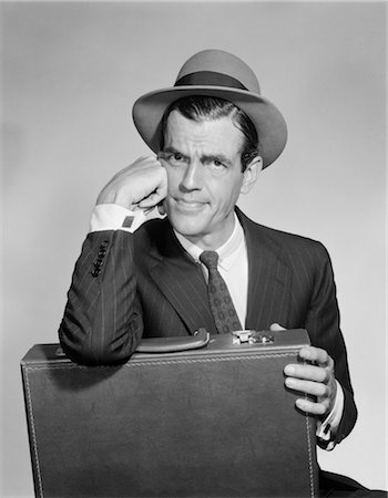 1950s SALESMAN HOLDING BRIEFCASE IN LAP RESTING ELBOW ON CASE RESTING FACE ON HAND WORRIED CONFUSED ANGRY WEARING HAT Stock Photo - Rights-Managed, Code: 846-02796848