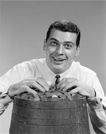 1960s MAN FUNNY FACE EXPRESSION SMILING HANDS ON TOP OF BARREL FILLED WITH COINS MONEY JACKPOT FINANCE WIN LOTTERY Stock Photo - Rights-Managed, Code: 846-02796965
