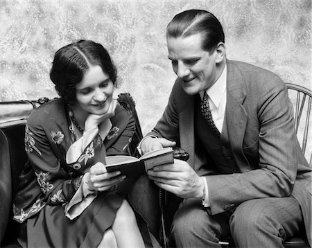 1920s 1930s COUPLE READING SHARING BOOK SMILING MAN POINTING OUT PASSAGE IN BOOK TO WOMAN FASHION CLOTHES Stock Photo - Rights-Managed, Code: 846-02797206