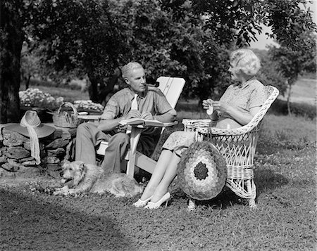 elderly lady talking to people - 1940s SENIOR RETIRED COUPLE SITTING OUTDOOR LAWN CHAIRS MAN SMOKING PIPE WOMAN KNITTING Stock Photo - Rights-Managed, Code: 846-02797201