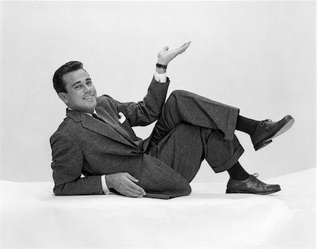 1950s MAN IN SUIT & TIE ON FLOOR LEANING BACK ON ELBOW WITH LEGS CROSSED & HAND IN AIR Stock Photo - Rights-Managed, Code: 846-02797230