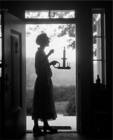 silhouette black and white - ANNÉES 1920 SILHOUETTE DE FEMME DEBOUT DANS L'EMBRASURE TRANSPORTANT BOUGEOIR Photographie de stock - Rights-Managed, Code: 846-02797418