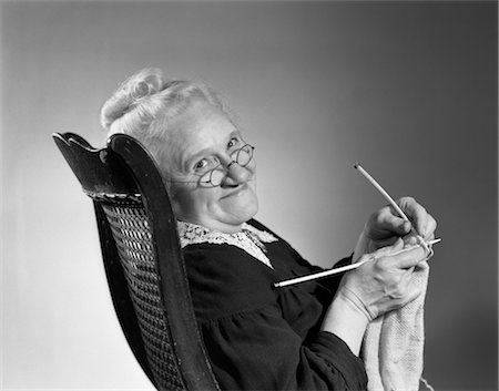 1950s 1960s SENIOR ELDERLY WOMAN KNITTING SMILING TURNING TO LOOK AT CAMERA GRANNY GLASSES Stock Photo - Rights-Managed, Code: 846-02797473