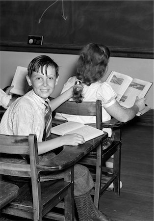 1940s 3 KIDS STUDENTS CLASSROOM BOYS GIRL FROM BACK ONE BOY TURNED SMILING AT CAMERA MISCHIEF OPEN BOOKS DESKS Stock Photo - Rights-Managed, Code: 846-02797553