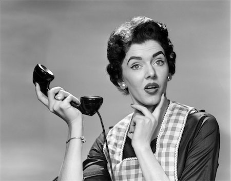 1950s CONFUSED WOMAN HOUSEWIFE HOLDING UP TELEPHONE RECEIVER FACIAL EXPRESSION Stock Photo - Rights-Managed, Code: 846-02797575
