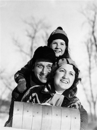 1930s MOTHER FATHER CHILD LYING ON TOBOGGAN FACING CAMERA SMILING HAT SCARF HOOD Stock Photo - Rights-Managed, Code: 846-02797846