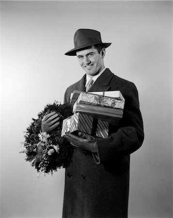simsearch:846-05648541,k - 1950s YOUNG MAN IN HAT COAT AND GLOVES HOLDING WREATH AND WRAPPED GIFTS Stock Photo - Rights-Managed, Code: 846-02797851