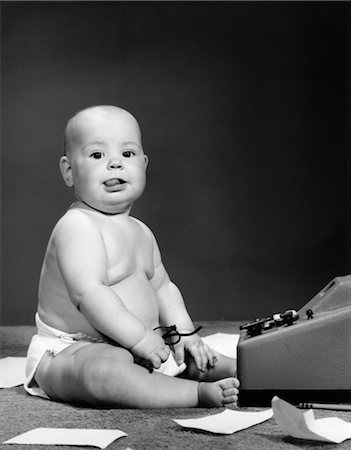 1950s BABY IN DIAPER STICKING OUT TONGUE HOLDING GLASSES SITTING BEFORE ADDING MACHINE Stock Photo - Rights-Managed, Code: 846-02791898