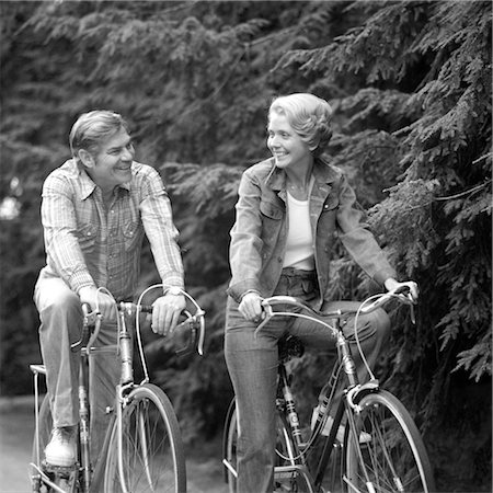 1970s HAPPY SMILING ACTIVE MATURE MIDDLE-AGED COUPLE RIDING BICYCLES BIKES PINE WOODED TRAIL ACTIVITY SPORTS RETIRE EXERCISE Stock Photo - Rights-Managed, Code: 846-02792027