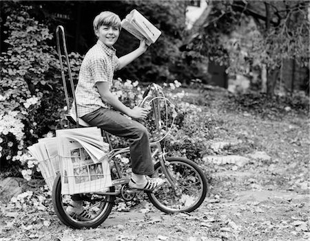 1970s SMILING DELIVERY NEWSBOY ON BICYCLE ABOUT TO TOSS NEWSPAPER LOOKING AT CAMERA Stock Photo - Rights-Managed, Code: 846-02792031