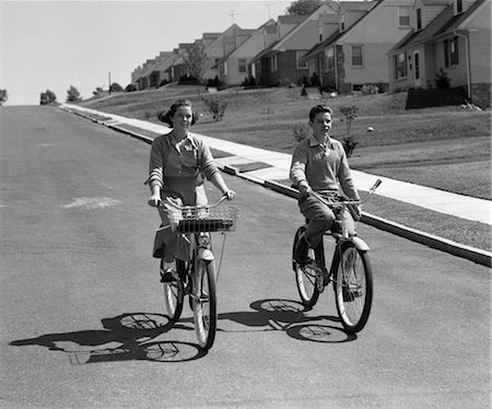 1950s TEEN BOY GIRL COUPLE RIDING BIKES DOWN RESIDENTIAL STREET Stock Photo - Rights-Managed, Code: 846-02792052