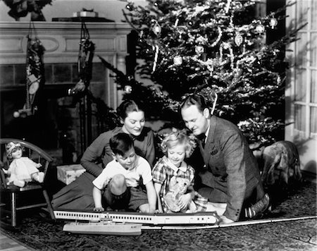 1930s FAMILY PLAYING WITH TOY TRAIN IN FRONT OF CHRISTMAS TREE FIREPLACE Stock Photo - Rights-Managed, Code: 846-02792160