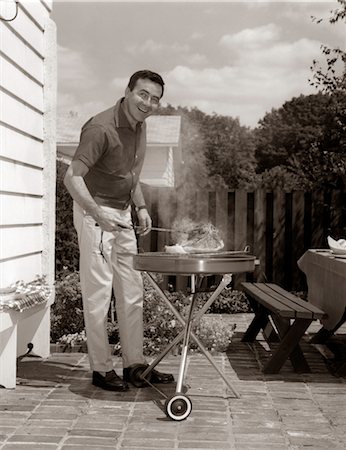 1960s HEAD-ON VIEW OF MAN BACKYARD PATIO COOKING STEAK ON GRILL Stock Photo - Rights-Managed, Code: 846-02792181