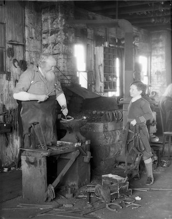 simsearch:846-02792220,k - 1930s ELDERLY BLACKSMITH WITH HAMMER AT ANVIL AS YOUNG BOY HOLDING HARNESS LOOKS ON SMILING Stock Photo - Rights-Managed, Code: 846-02792221