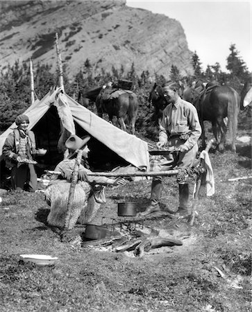 simsearch:846-02793153,k - 1920s 1930s TWO MEN AND ONE WOMAN EATING A MEAL AROUND A CAMPFIRE WITH A TENT AND HORSES AT BAKER LAKE ALBERTA CANADA Stock Photo - Rights-Managed, Code: 846-02792250