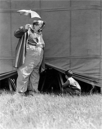 1930s MAN CLOWN CATCHING LITTLE BOY PEEKING UNDER CIRCUS BIG TOP TENT Foto de stock - Con derechos protegidos, Código: 846-02792292